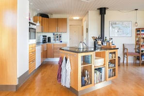 A modern kitchen with wooden cabinets, a central island, and a coffee machine. - Holiday home with sunset views near Hvidbjerg (Børkop)