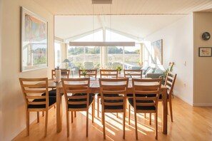A dining area with a wooden table and chairs, large windows, and artwork on the walls. - Holiday home with sunset views near Hvidbjerg (Børkop)