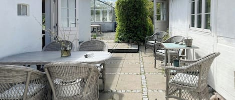 Eine Terrassengruppe mit Korbmöbeln, einem Tisch und Stühlen.