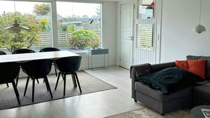 Ein modernes Wohnzimmer mit Essbereich, einer Couch und Blick ins Freie.