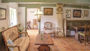 Una stanza con un tavolo di legno, un divano, una sedia, una sveglia e un quadro appeso al muro.