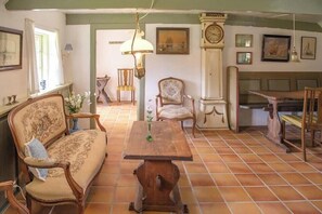 A room with a wooden table, a sofa, a chair, a clock, and a painting on the wall. - ‘Knøv’ country retreat with seaweed roof on Læsø (Læsø)
