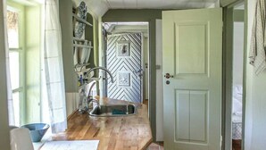 Una cucina con piano di lavoro in legno, lavello e pavimento piastrellato.