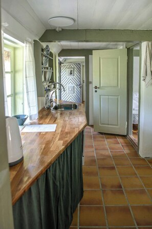 A kitchen with a wooden countertop, a sink, and a tiled floor. - ‘Knøv’ country retreat with seaweed roof on Læsø (Læsø)