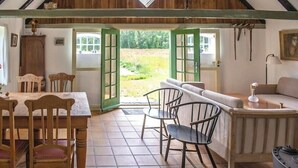 Un arredamento rustico con un tavolo da pranzo, sedie, un divano e una vista attraverso porte aperte.