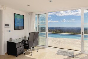 A modern office with a desk, chair, and a large window with a city view. - Villa with panoramic view over Cannes (Spéracèdes)