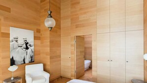 Een moderne badkamer met houten lambrisering, een witte badkuip en een grote zwart-wit foto aan de muur.