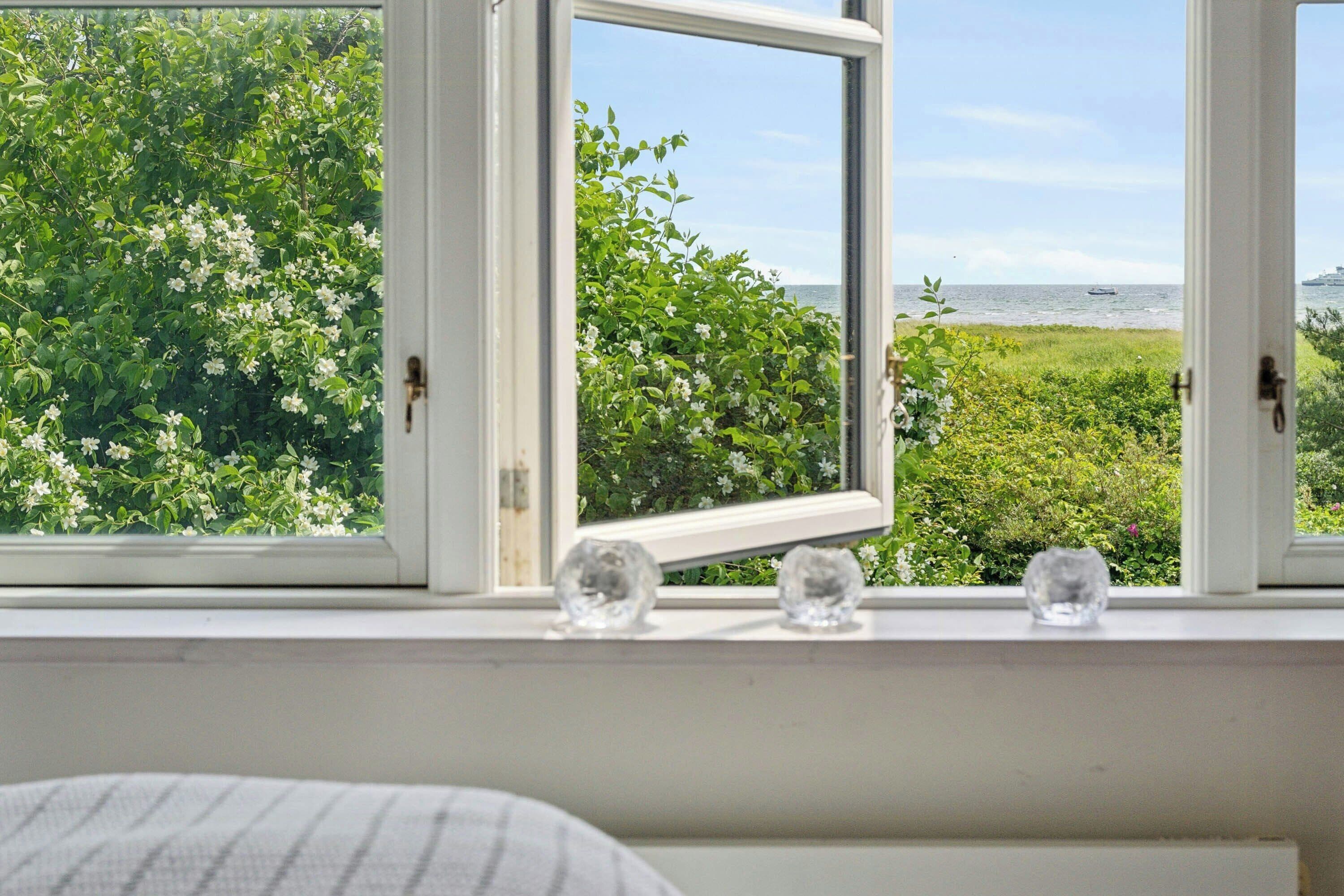 A window with a view of a garden and the sea.