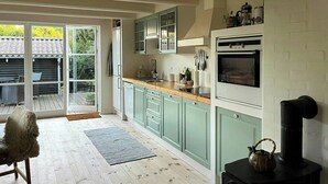 Une cuisine équipée d’une cuisinière, d’un four et où se trouve un chien.