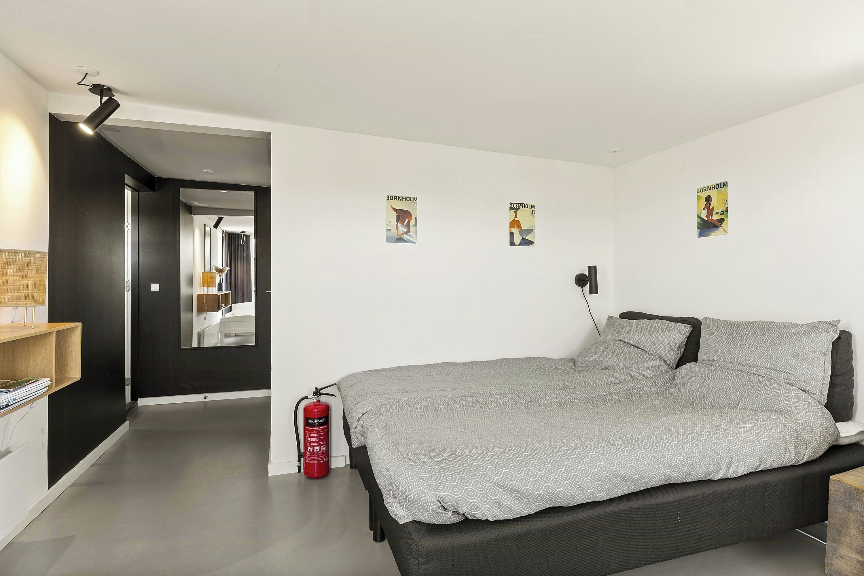 Ein modernes Schlafzimmer mit Bett, Feuerlöscher und Wandbildern.