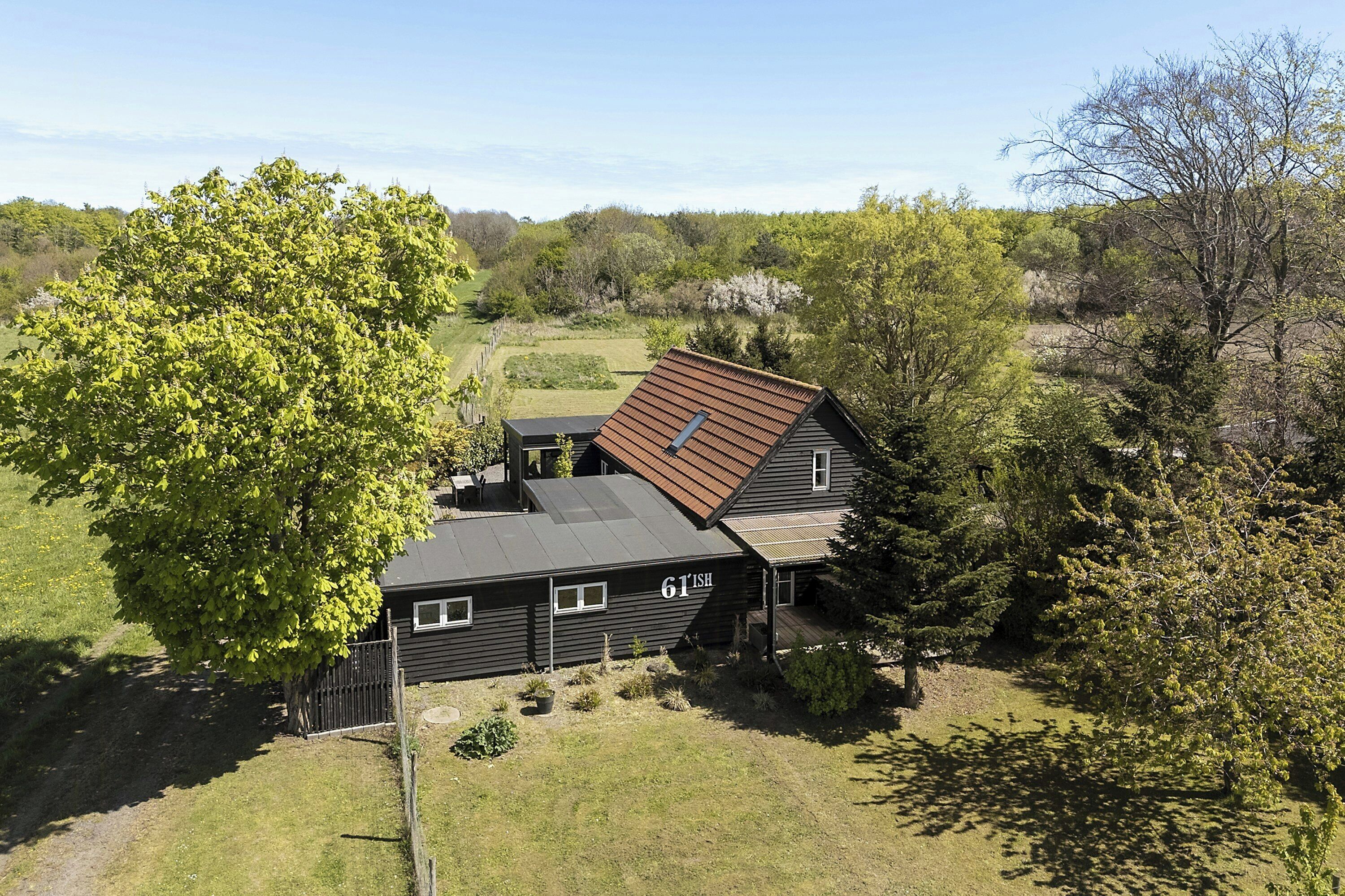 A house with a sloped roof, surrounded by trees and a grassy yard.