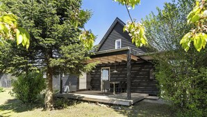 Eine Holzjagdhaus mit überdachter Veranda, einem kleinen Fenster und einem Rasen.