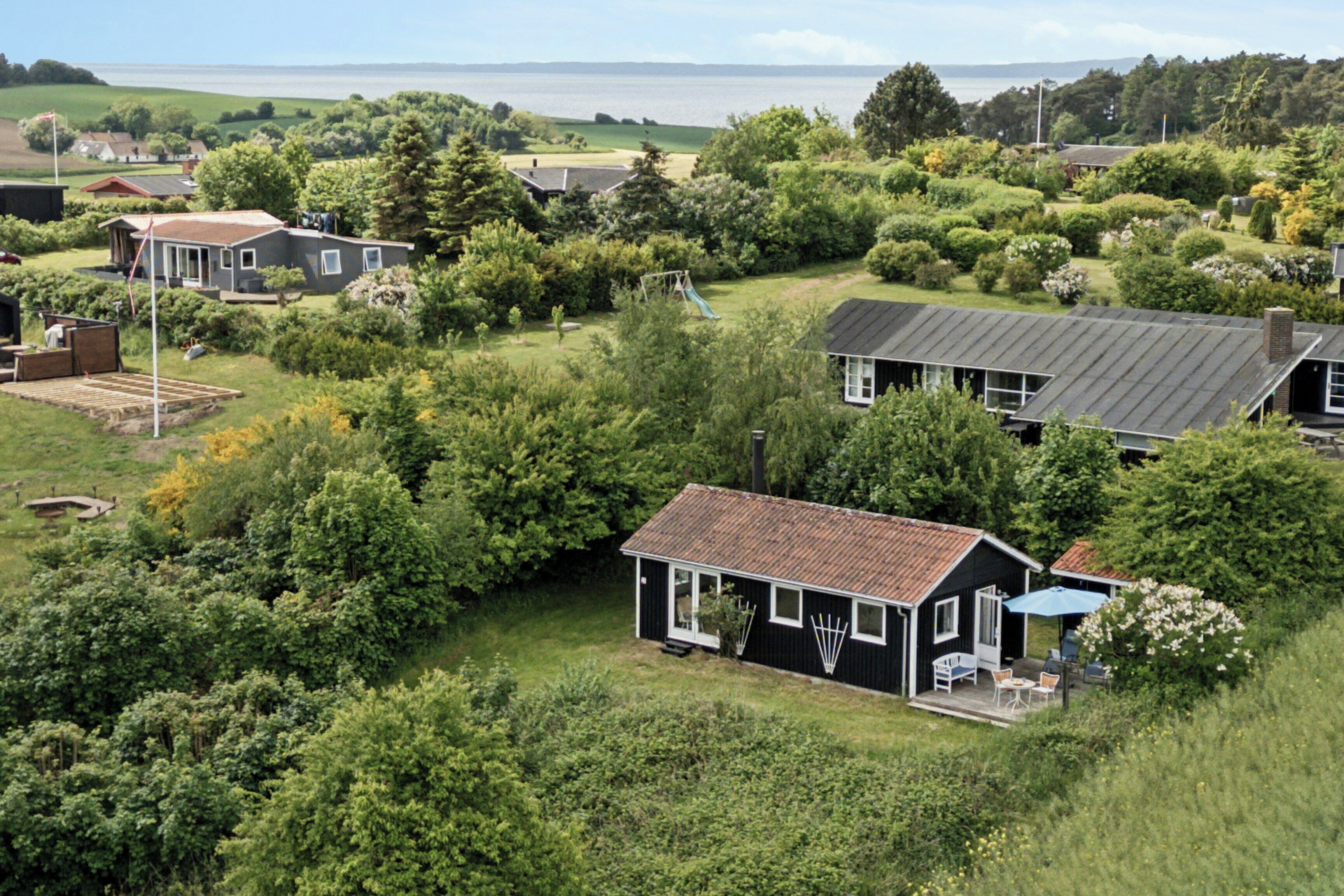 A residential area with houses surrounded by greenery, a playground, and a view of the sea.