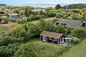 A residential area with houses surrounded by greenery, a playground, and a view of the sea. - Holiday home with view over Mols hills (Knebel)
