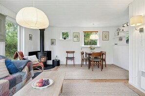 Una sala de estar acogedora con chimenea, comedor y un amplio ventanal con vistas a la vegetación.