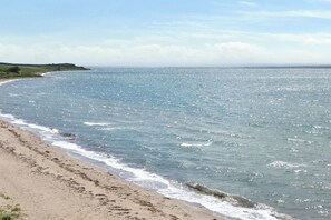 A beach with waves, a clear sky, and distant hills. - Holiday home with view over Mols hills (Knebel)