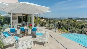 Um pátio com mobiliário exterior, piscina e vista para a paisagem.