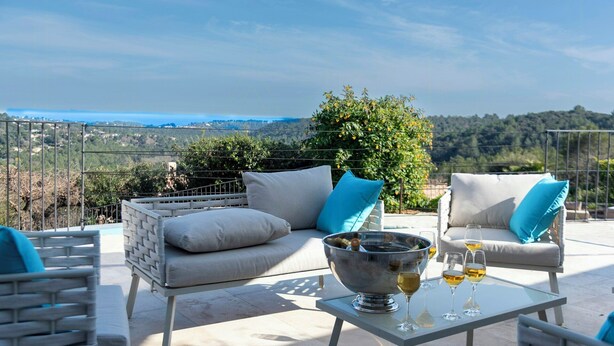 Um terraço com mobiliário de exterior, uma mesa com copos e vista para a paisagem.