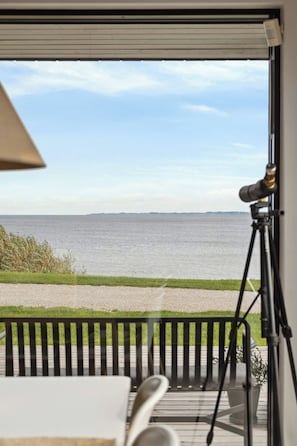 Ein Balkon mit Meerblick, einem Teleskop und einem Stuhl.