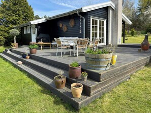 Une terrasse dotée de mobilier d’extérieur, de plantes en pot et offrant une vue sur une maison.