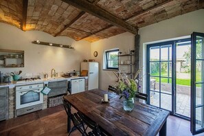 Eine rustikale Küche mit Holztisch, integrierten Geräten und Blick ins Freie.