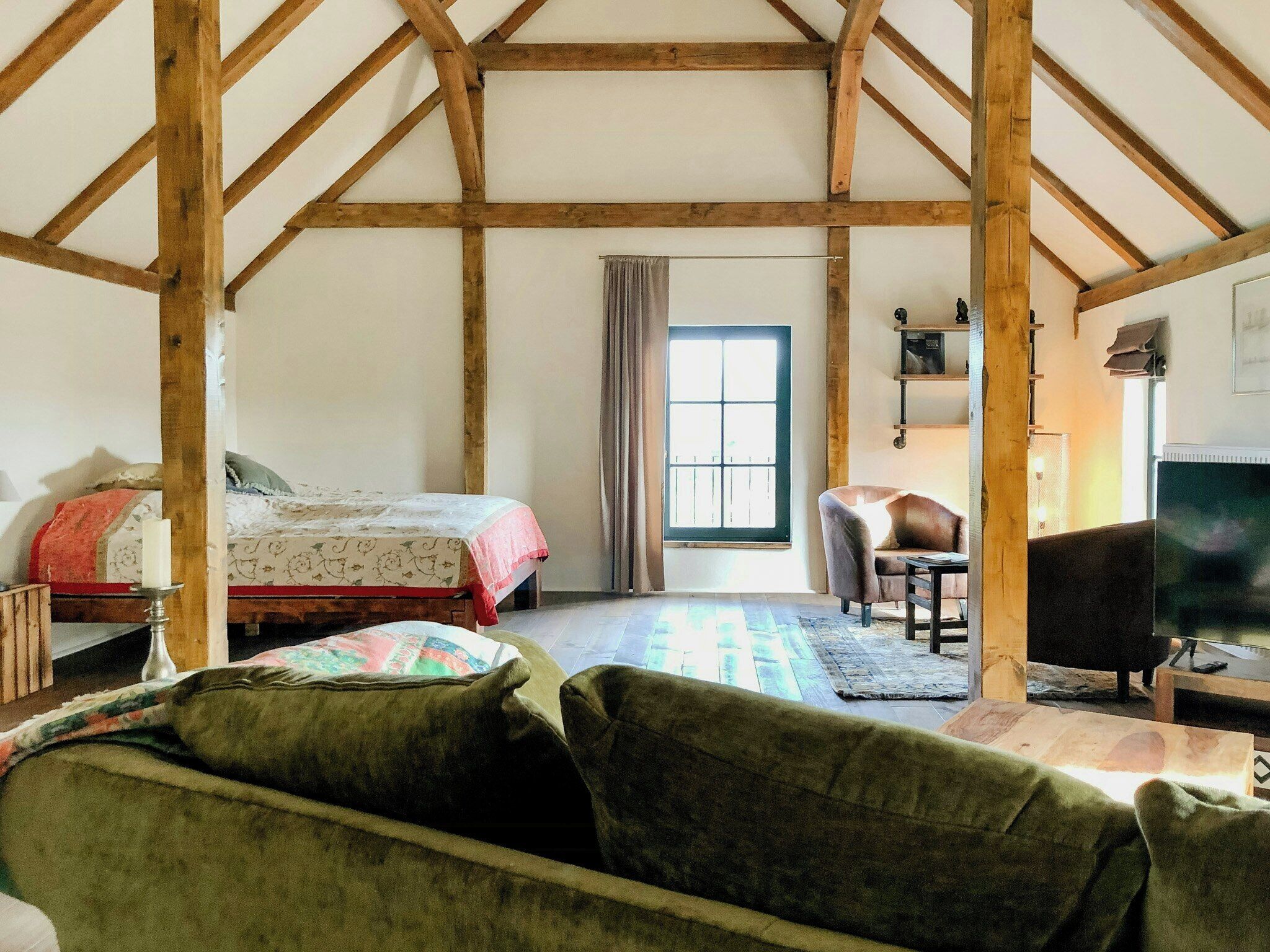 A room with a bed, a chair, a television, and a window.