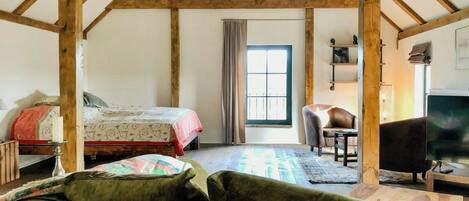 A room with a bed, a chair, a television, and a window.