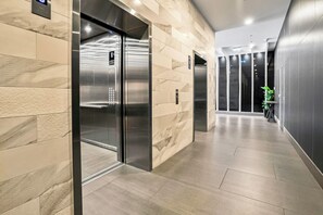 A modern elevator with a digital display, a marble wall, and a clean, tiled floor. - 2BR CBD Escape-Pool, Gym & 17th floor views (Adelaide)