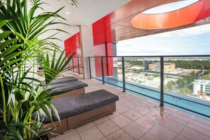 A balcony with wicker furniture, a glass railing, and a view of a cityscape. - 2BR CBD Escape-Pool, Gym & 17th floor views (Adelaide)