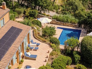 Ein Wohnhaus mit Schwimmbad, Sitzgelegenheiten im Freien und üppigem Grün.
