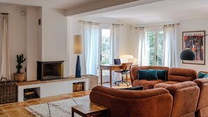 Een woonkamer met een bank, een open haard, een bureau met stoel en een lamp.