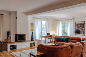 Ein Wohnzimmer mit einer Couch, einem Kamin, einem Schreibtisch mit Stuhl und einer Lampe.