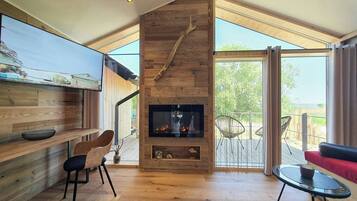 A modern interior with a fireplace, wooden walls, and a balcony with outdoor seating.