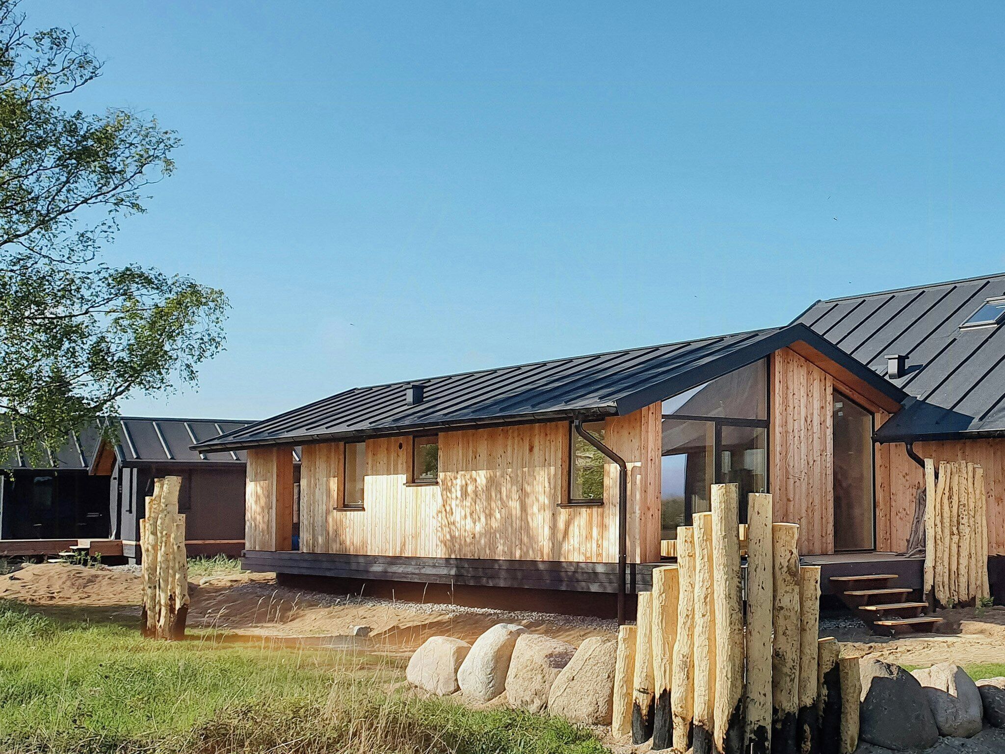 A wooden cabin with a sloped roof, large windows, and a stone foundation.