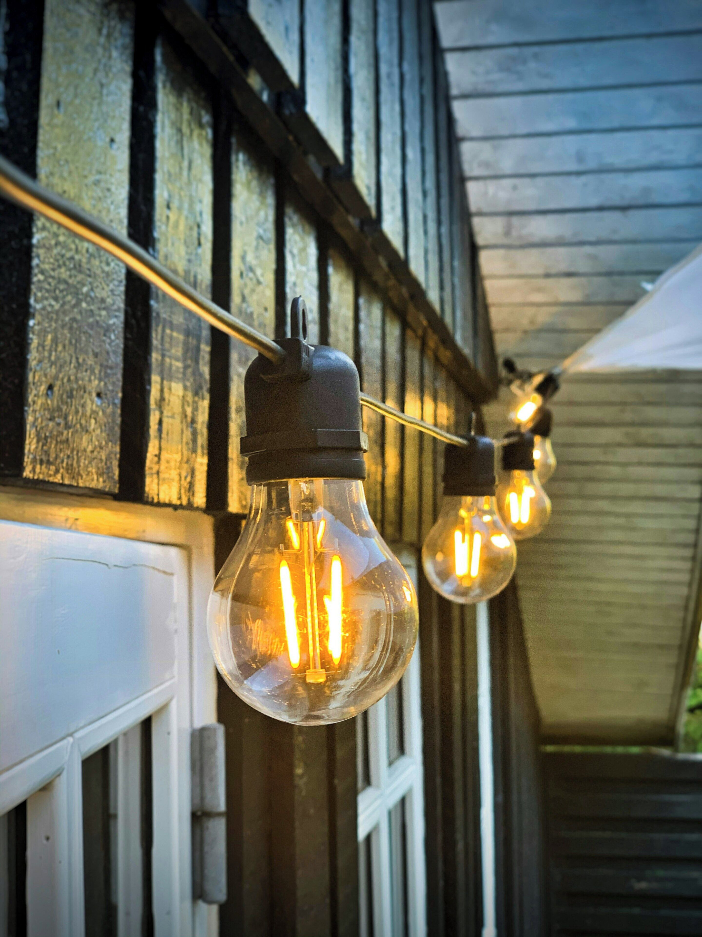 Une guirlande de petites lampes suspendue à un mur extérieur en bois.
