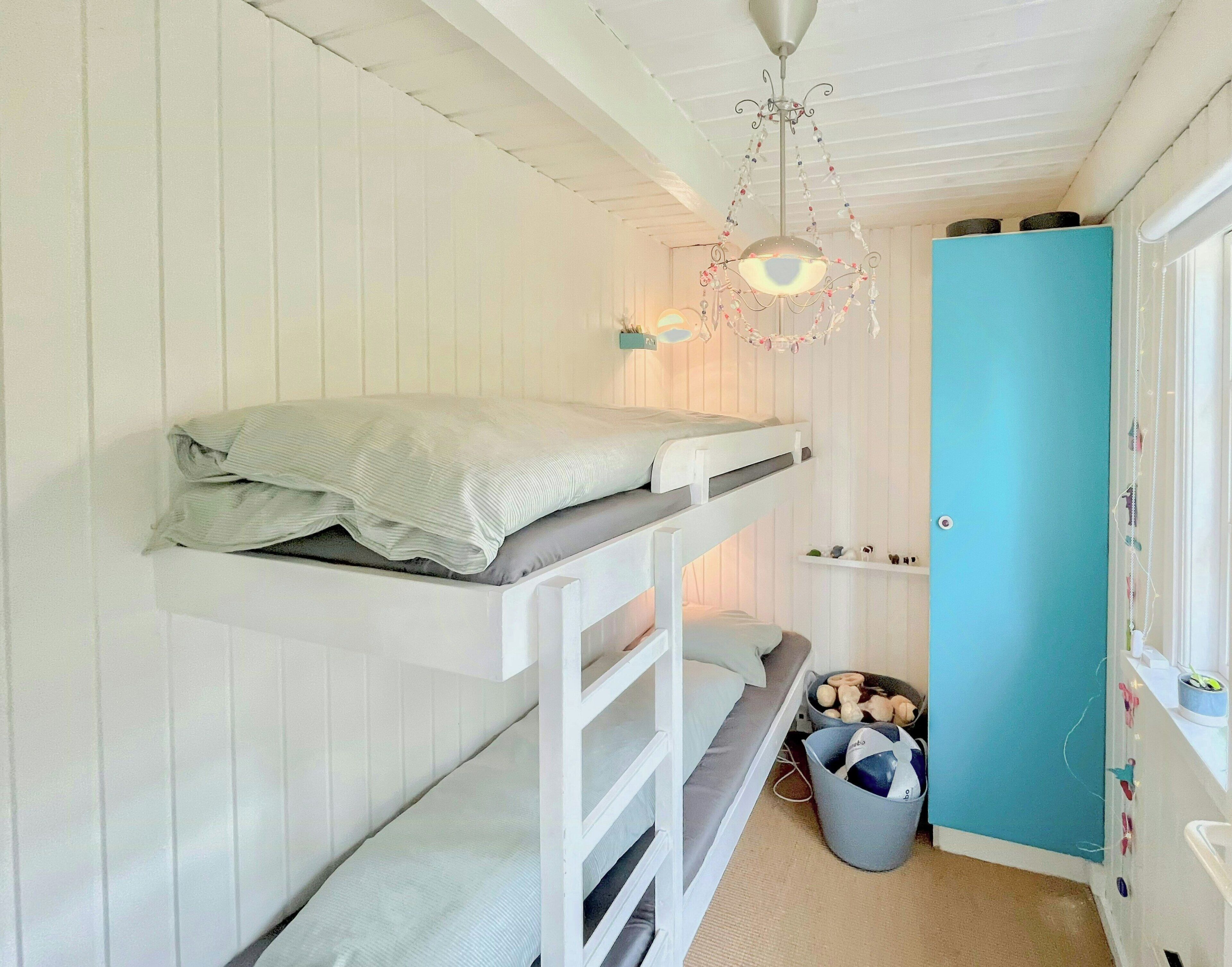 A bunk bed room with a ceiling fan, a blue door, and a small window.