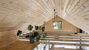 Een houten interieur met een schuine kap, een potplant en een raam.