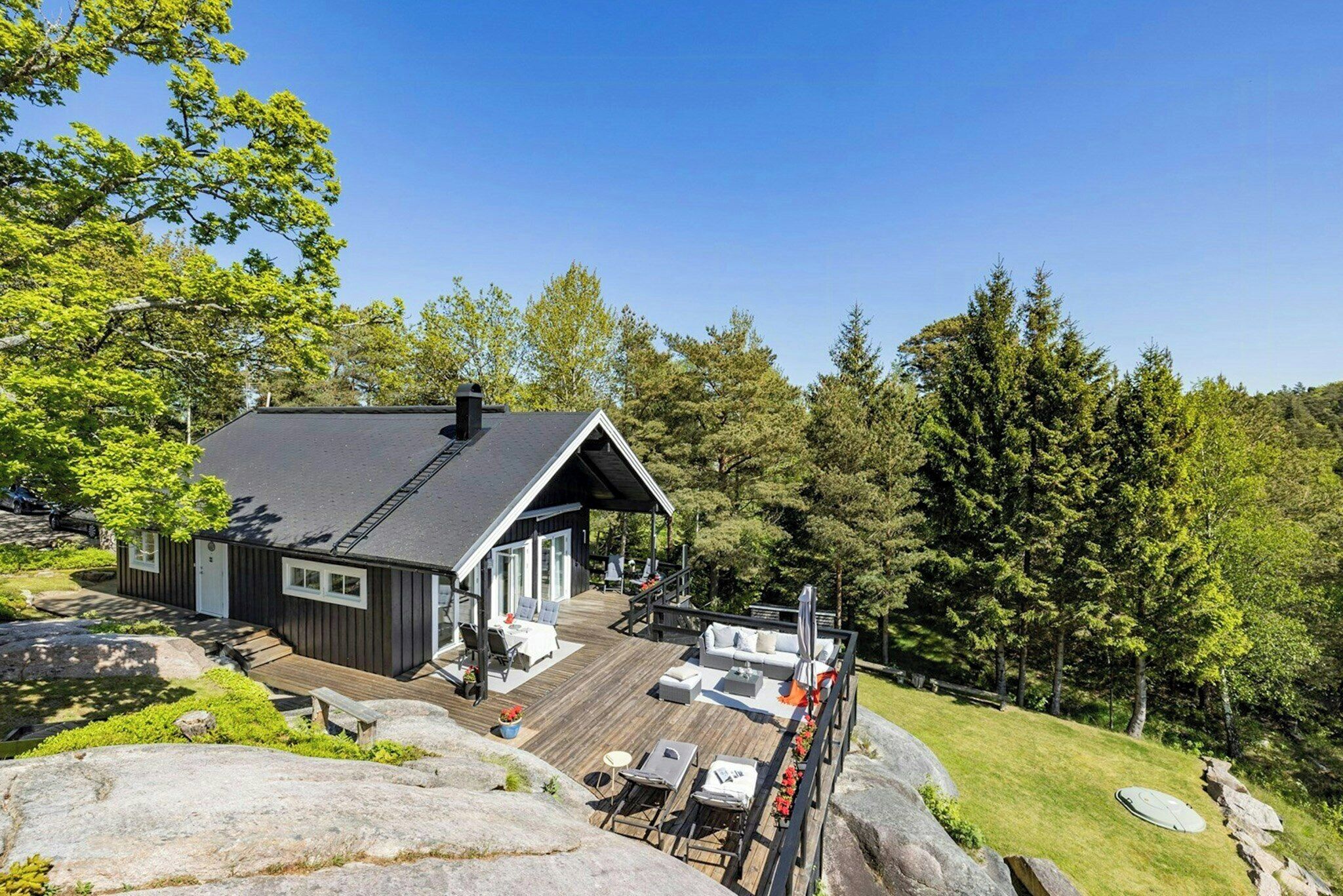 Uma cabana com varanda, área de estar externa e vista para a floresta ao redor.