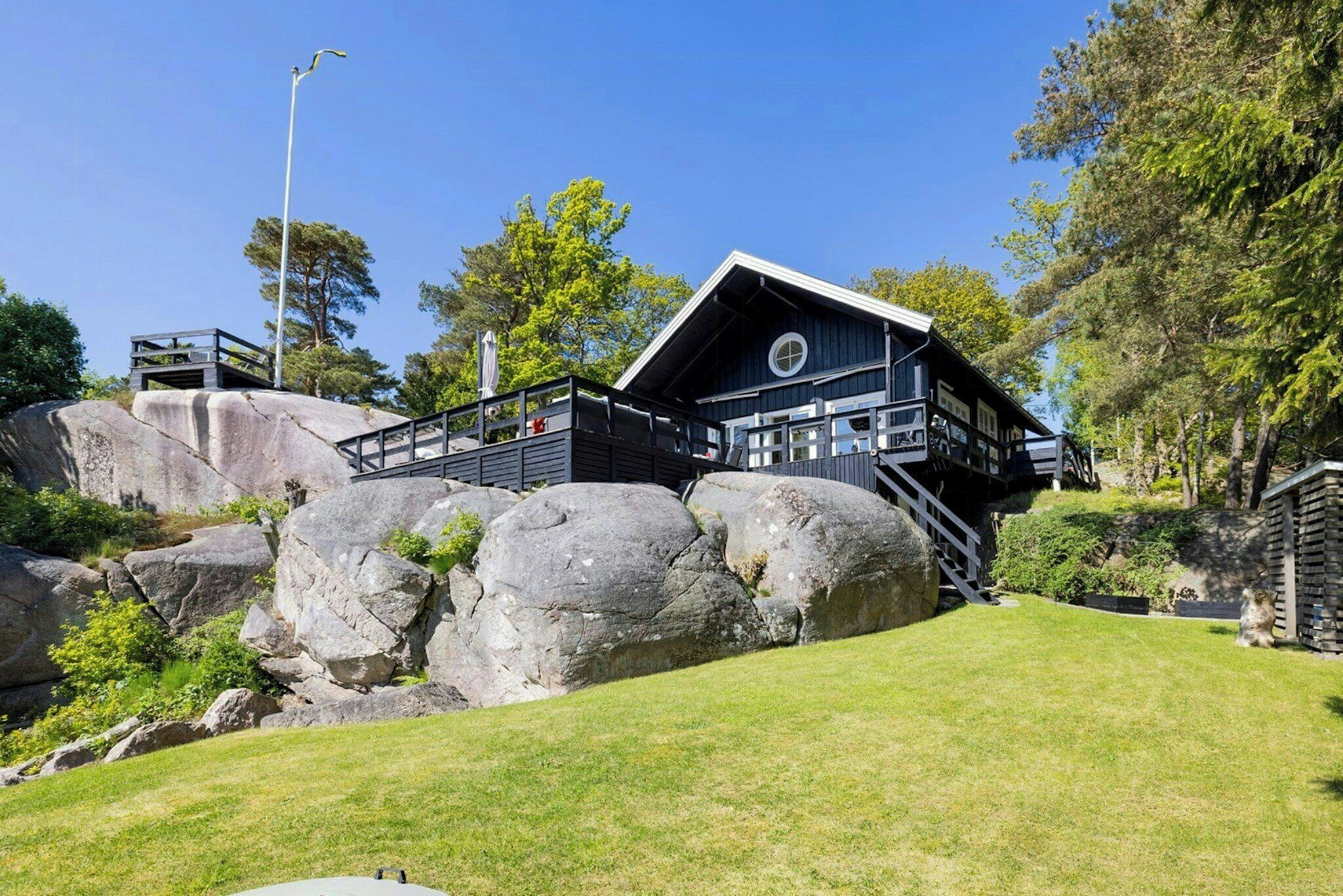 A modern building with a deck, large rocks, and a well-maintained lawn.