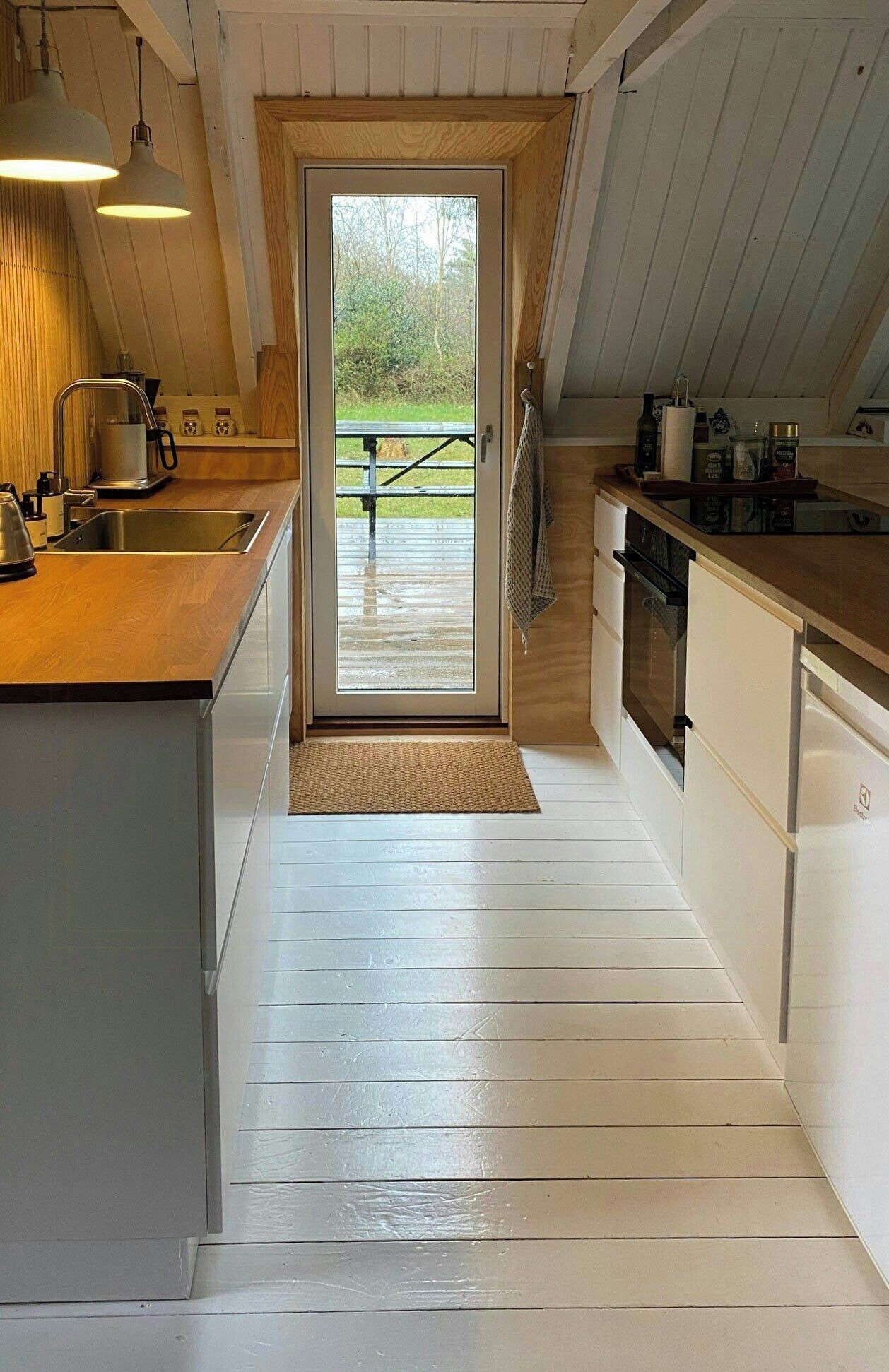 Una cocina moderna con encimera de madera, electrodomésticos de acero inoxidable y vistas a una terraza exterior.
