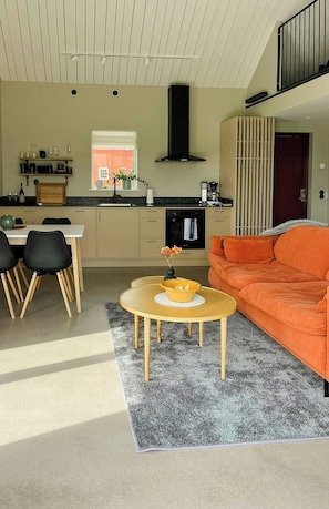 A modern kitchen with a dining area, a sofa, and a coffee table. - Rural cottage with views over Herrljunga (Ljung)
