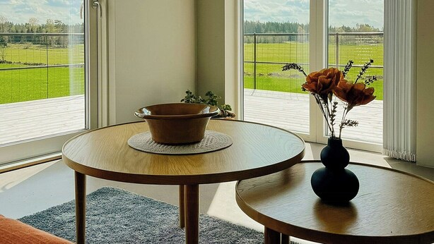 A room with a round table, a bowl, and a vase with flowers.