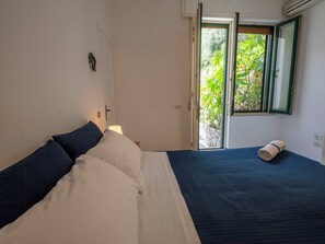 A bedroom with a bed, a window, and a door. - Sea view house with lemon grove in Atrani (Ravello)