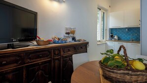 Een moderne keuken met een flatscreen-tv, houten keukenkastjes, een eettafel en een mandje met citroenen.