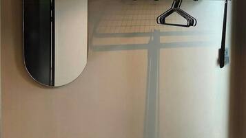 Une salle de bain équipée d’un miroir, d’un porte-serviettes, d’une étagère et d’un porte-chaussures.