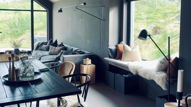 Un interior moderno con comedor, sofá y ventana con vistas a zonas verdes.