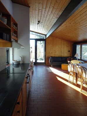 Eine moderne Küche mit einer großen Kochinsel, Holzwänden und einem Essbereich mit Tisch und Stühlen.