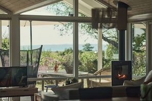 Ein gemütliches Zimmer mit großem Fenster, Kamin und Fernseher.