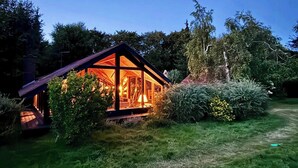 A wooden cabin with a glass front, surrounded by greenery. - Traditional Kalmar house close to the beach (sjaellands odde)