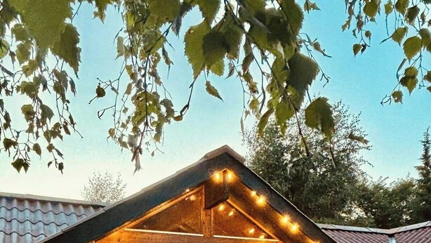 A wooden deck with a table and chairs, a hanging light fixture, and a covered area with windows. - Traditional Kalmar house close to the beach (sjaellands odde)